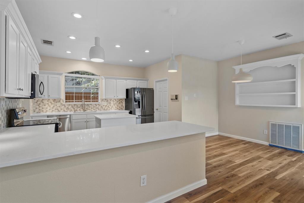1719 Live Oak Lane Allen, TX 75002 - Photo 13 of 38 a large white kitchen with kitchen island a sink wooden floor and a refrigerator