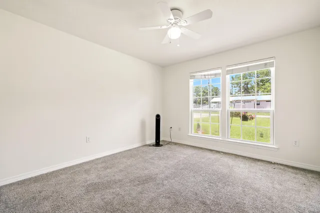an empty room with a window and a ceiling fan