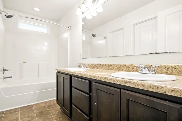 a bathroom with a granite countertop sink a large mirror and a bathtub