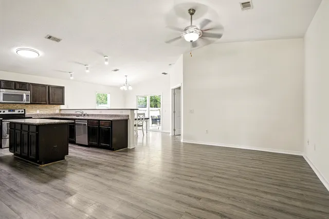 a large kitchen with stainless steel appliances granite countertop a stove cabinets and wooden floor