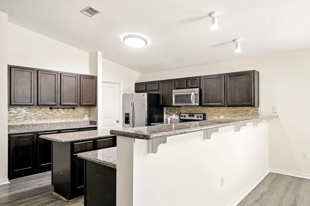 a kitchen with stainless steel appliances granite countertop a sink stove and refrigerator