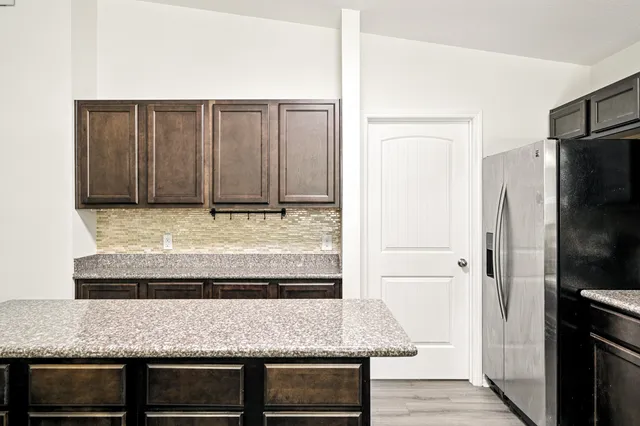 a kitchen with granite countertop a refrigerator and stove