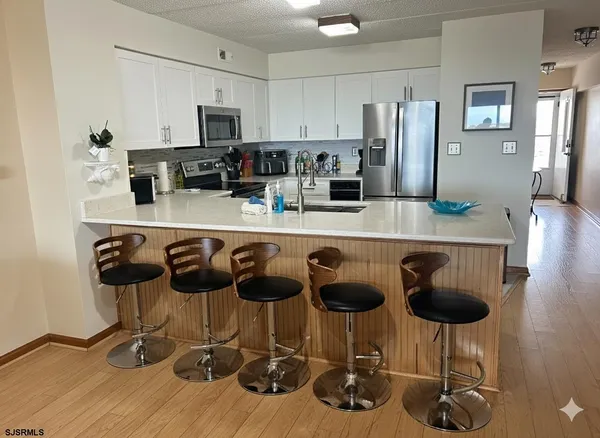 a kitchen with stainless steel appliances granite countertop a stove a refrigerator a sink a dining table and chairs