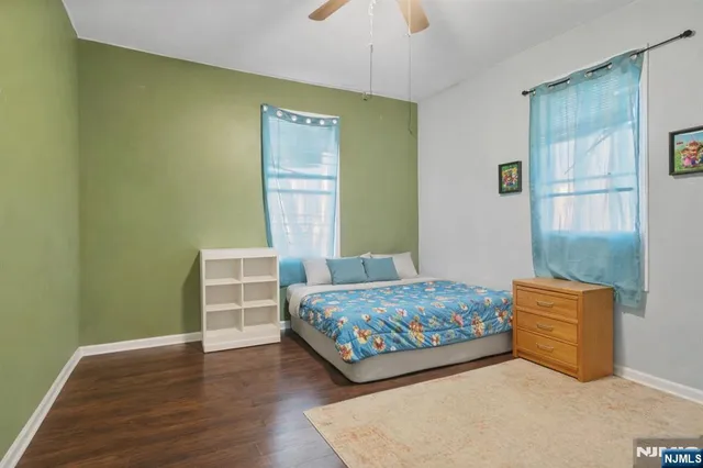 a bedroom with a bed window and a flat tv screen on a dresser