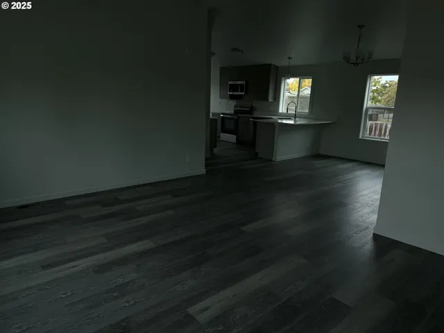 an empty room with wooden floor fireplace and windows