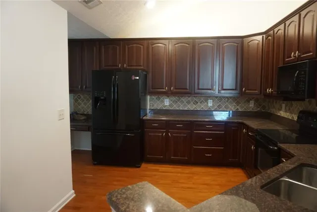 a kitchen with stainless steel appliances granite countertop a refrigerator and a stove top oven