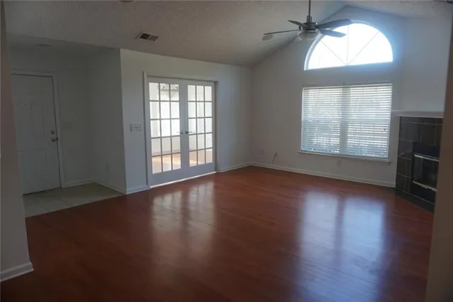 an empty room with wooden floor and windows
