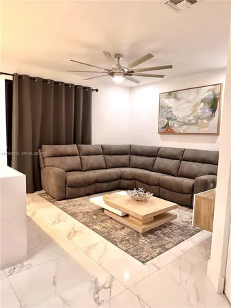 a living room with furniture a rug and a ceiling fan