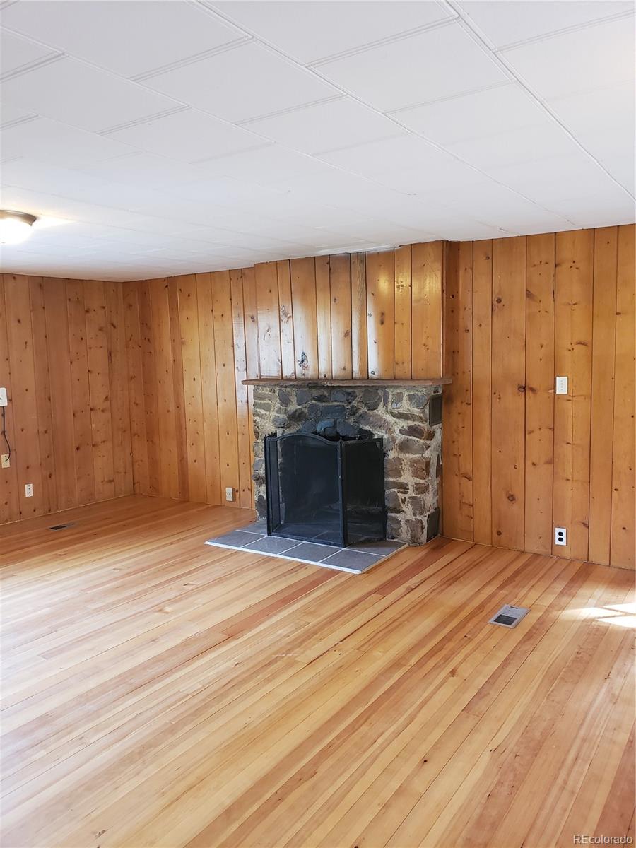 11769 Ranch Elsie Road Golden, CO 80403 - Photo 12 of 39 an empty room with wooden floor fireplace and windows