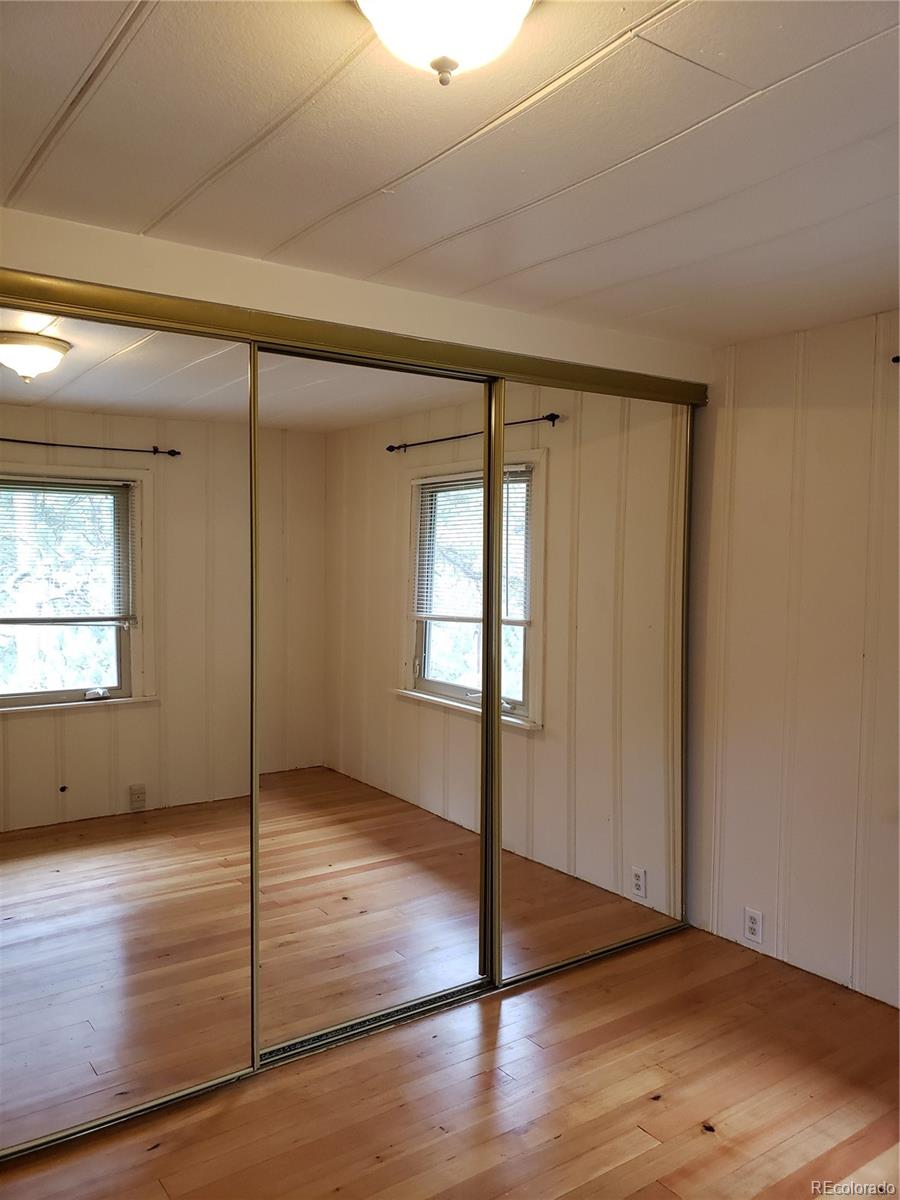 11769 Ranch Elsie Road Golden, CO 80403 - Photo 21 of 39 an empty room with wooden floor and sliding door