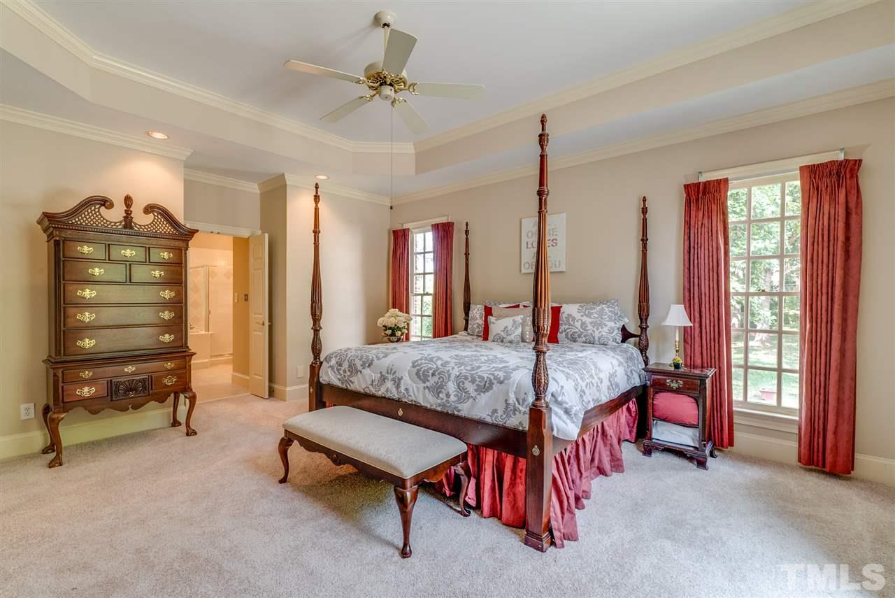 8912 Carnoustie Way Raleigh, NC 27613 - Photo 11 of 25 a bedroom with a bed a chandelier and a dresser