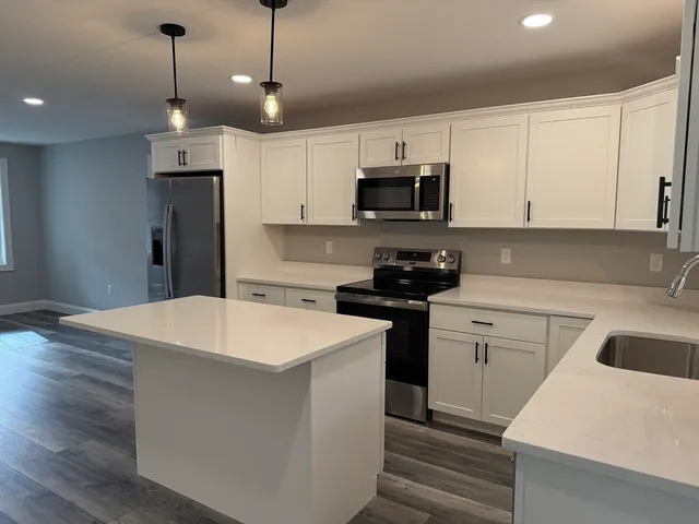 a kitchen with kitchen island a sink stainless steel appliances and white cabinets