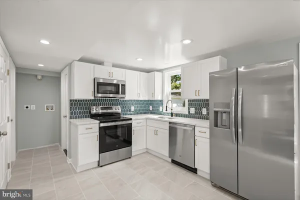 a kitchen with stainless steel appliances granite countertop a refrigerator a stove a sink and a microwave