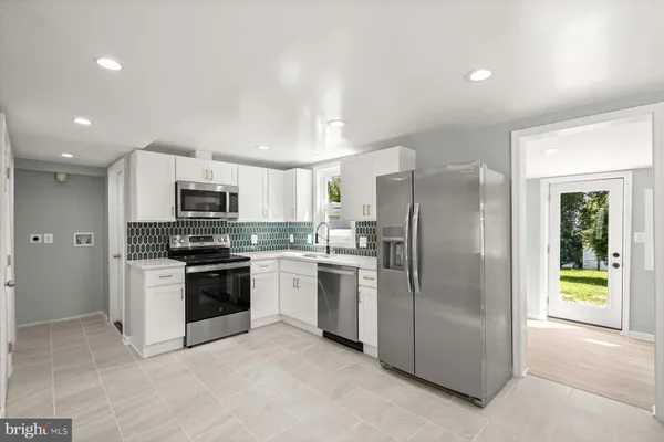 a kitchen with stainless steel appliances granite countertop a refrigerator a stove a sink and a microwave