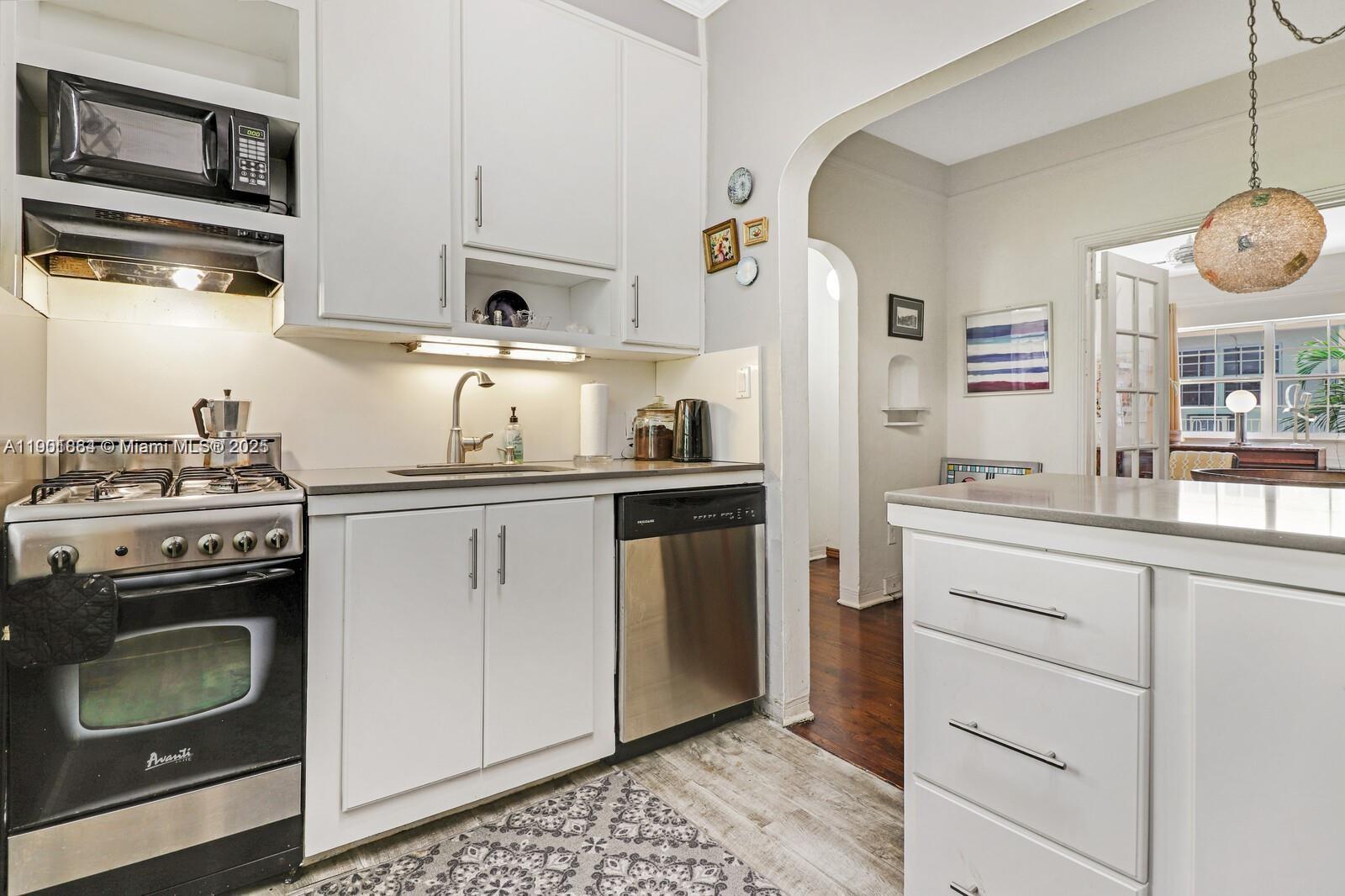 1250 Drexel Avenue, Unit 7 Miami Beach, FL 33139 - Photo 18 of 30 a kitchen with cabinets stainless steel appliances and wooden floor