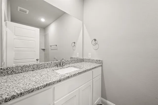 a bathroom with a granite countertop sink and a mirror
