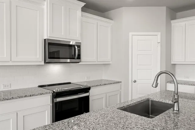 a kitchen with granite countertop white cabinets stainless steel appliances and sink