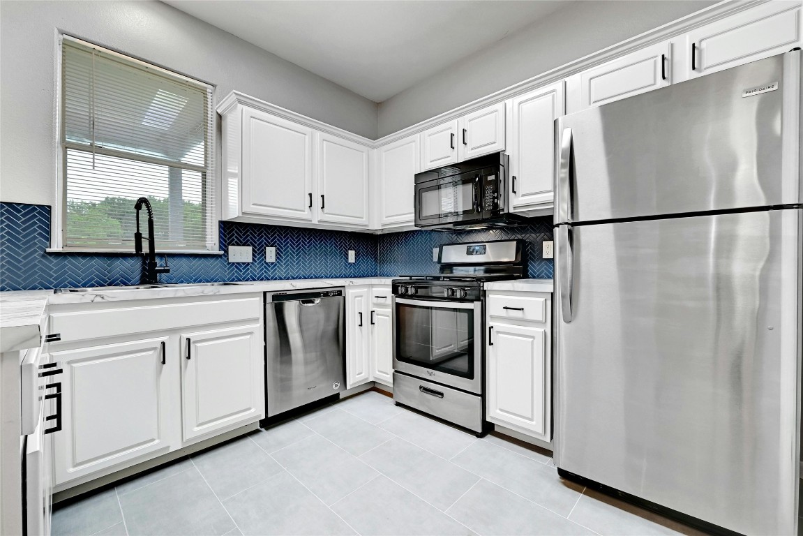 5716 West Gate Boulevard, Unit A Austin, TX 78745 - Photo 1 of 1 a kitchen with white cabinets stainless steel appliances and a refrigerator