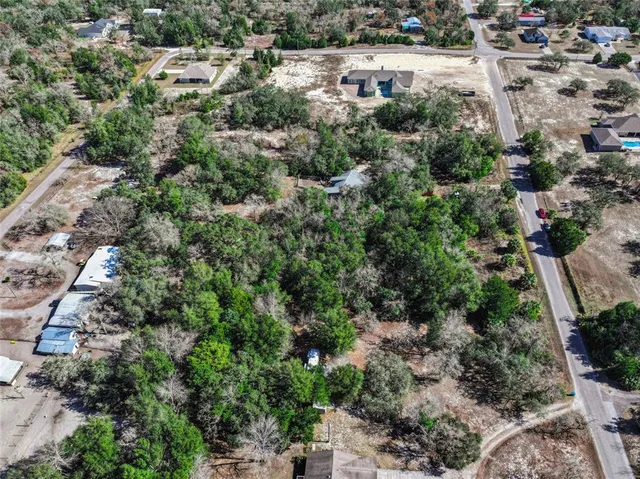 an aerial view of residential house with outdoor space and trees all around