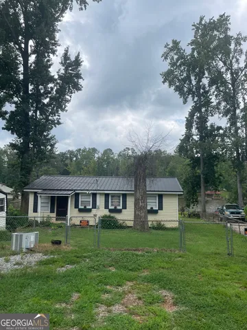 a front view of a house with a garden and trees
