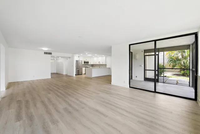 a view of an empty room with a window and wooden floor