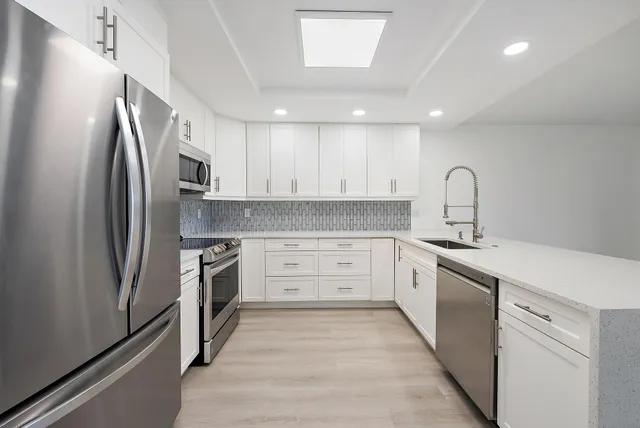 a kitchen with white cabinets and wooden floors