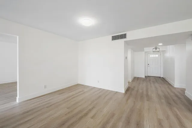a view of empty room with wooden floor and fan