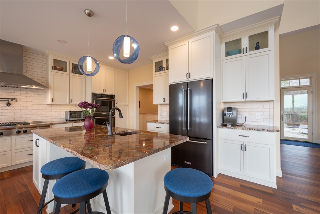 1089 Westhampton Road Northampton, MA 01062 - Photo 18 of 42 a kitchen with stainless steel appliances granite countertop a stove refrigerator a sink dishwasher a dining table and chairs with wooden floors