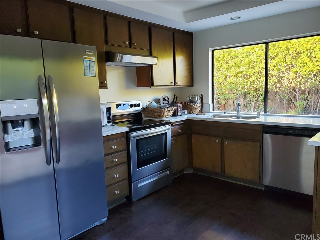 5001 Paseo Dali Irvine, CA 92603 - Photo 11 of 20 a kitchen with stainless steel appliances granite countertop a stove a refrigerator a sink a stove with wooden cabinets