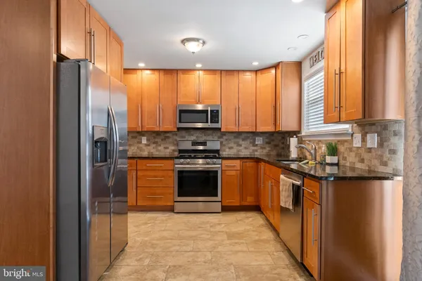 a kitchen with stainless steel appliances granite countertop a refrigerator a stove and a sink