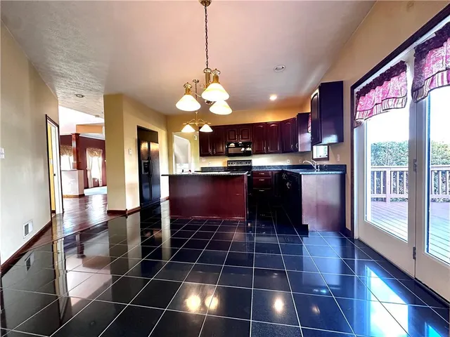 a kitchen with stainless steel appliances a sink a stove a refrigerator cabinets and dining table