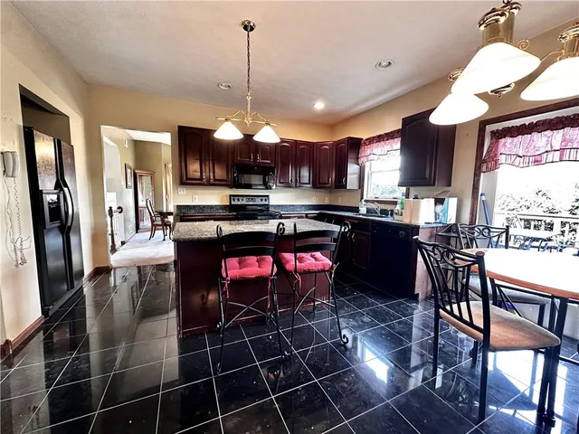 a kitchen with stainless steel appliances a stove a sink dishwasher a dining table and chairs with wooden floor