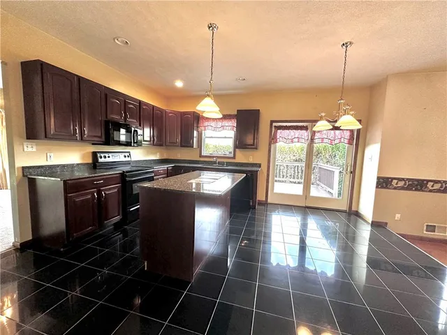 a kitchen with stainless steel appliances granite countertop a stove a sink and a microwave