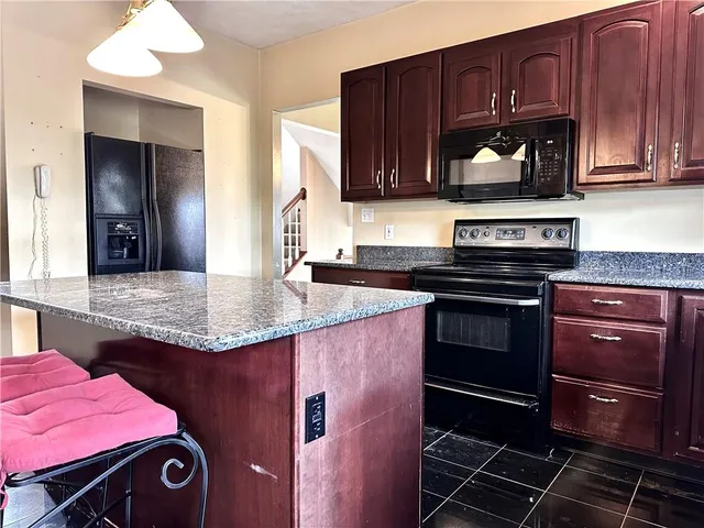 a kitchen with granite countertop stainless steel appliances a stove a sink and cabinets