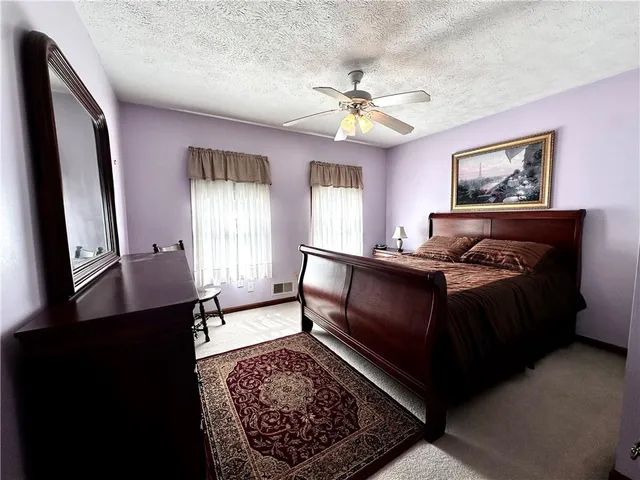 a bedroom with a bed a dresser with wooden floor