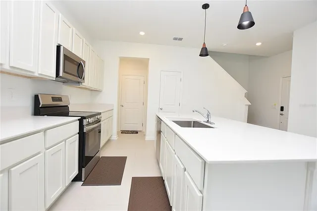 a kitchen with a sink dishwasher and white cabinets with wooden floor