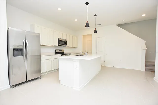 a kitchen with stainless steel appliances a refrigerator sink and white cabinets