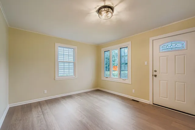 a view of an empty room with a window and wooden floor