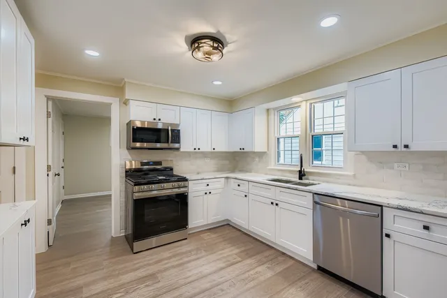 a kitchen with granite countertop white cabinets and stainless steel appliances