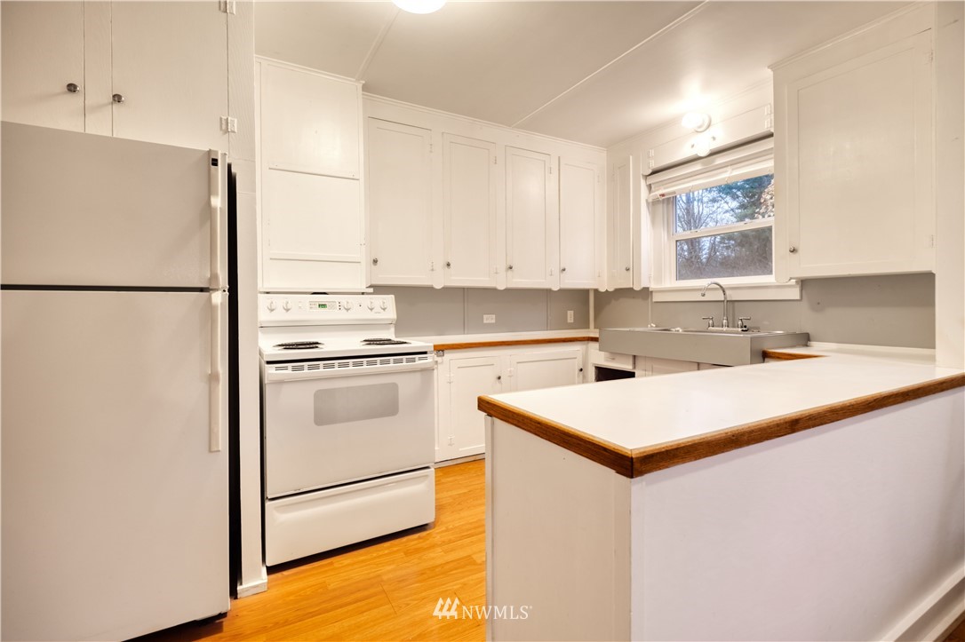 340 Boundary Bay Road Point Roberts, WA 98281 - Photo 8 of 17 a kitchen with a sink a stove a refrigerator and white cabinets