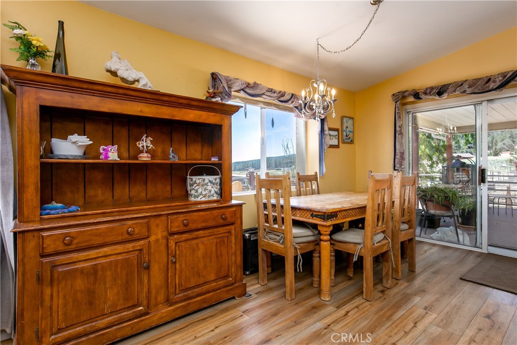 10960 Steinhoff Road Frazier Park, CA 93225 - Photo 24 of 46 The warm and inviting dining space showcases an open layout with beautiful wood-look flooring and soft yellow-toned walls. It features a rustic wooden dining table set and a matching large wooden display hutch, while a wide sliding glass door fills the room with natural light and provides direct access to the outdoor deck.