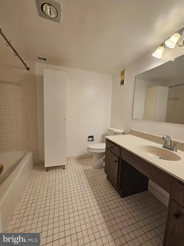 an empty room with wooden floor and bathroom view