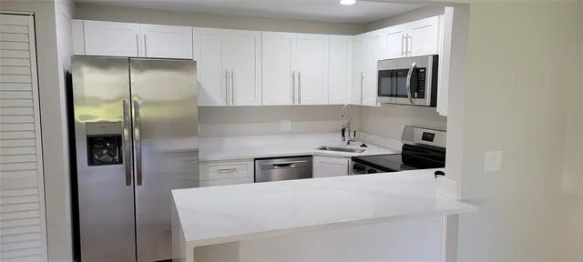 a kitchen with kitchen island a sink stainless steel appliances and cabinets