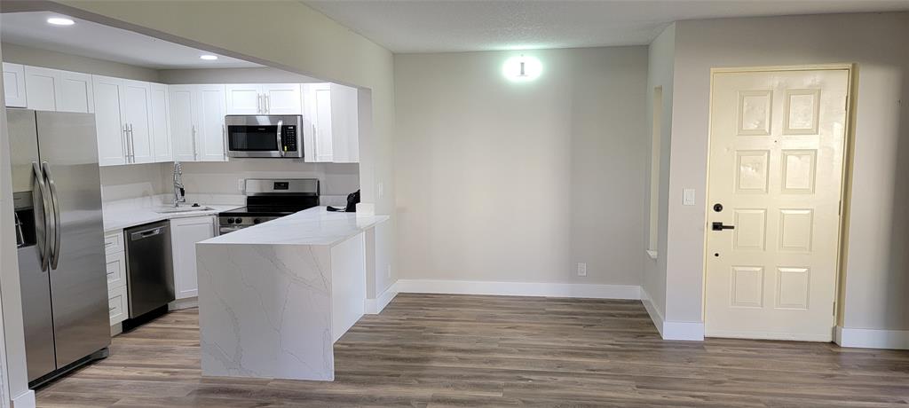 4829 Sable Pine Circle, Unit 1C West Palm Beach, FL 33417 - Photo 13 of 16 a room with stainless steel appliances a refrigerator a stove top oven a sink and dishwasher