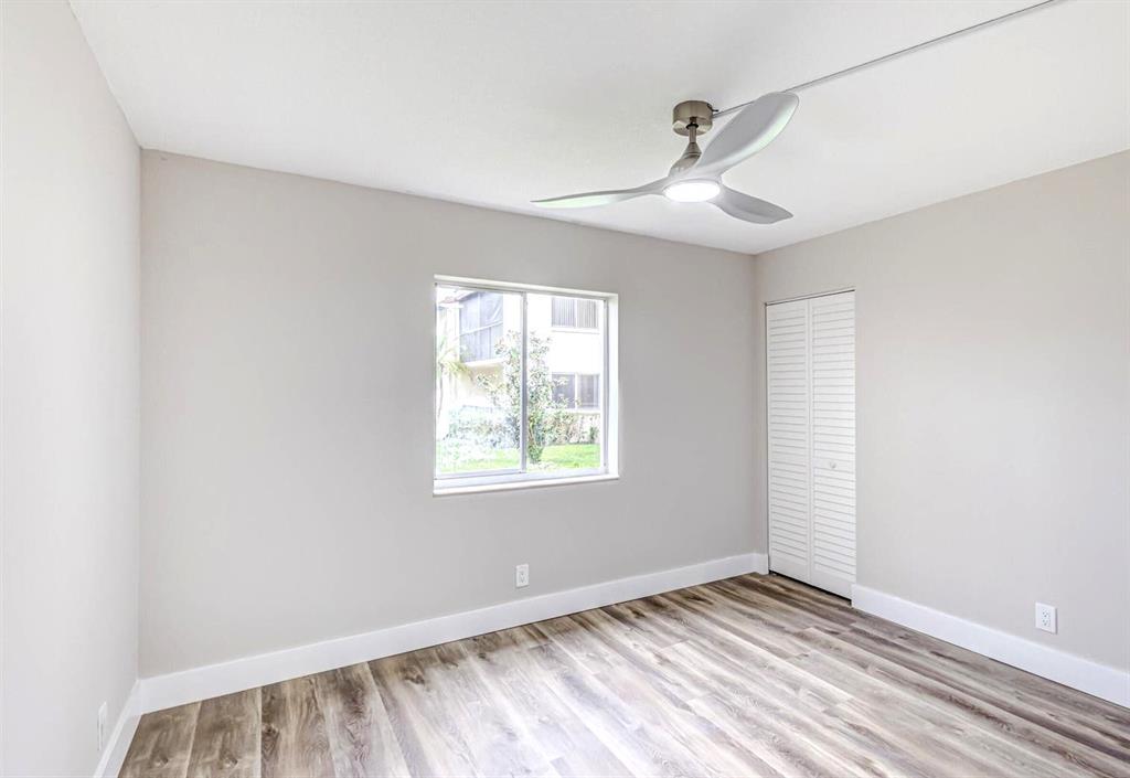 4829 Sable Pine Circle, Unit 1C West Palm Beach, FL 33417 - Photo 14 of 16 a view of an empty room with wooden floor and a window