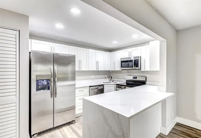 a kitchen with a refrigerator a microwave a sink and cabinets