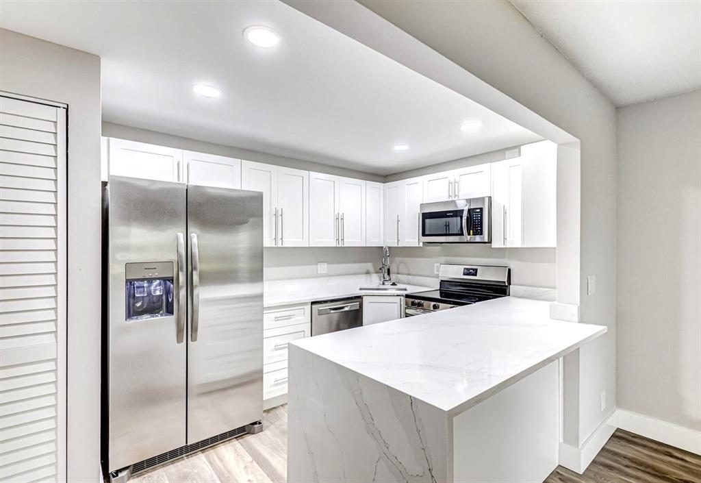 4829 Sable Pine Circle, Unit 1C West Palm Beach, FL 33417 - Photo 6 of 16 a kitchen with a refrigerator a microwave a sink and cabinets