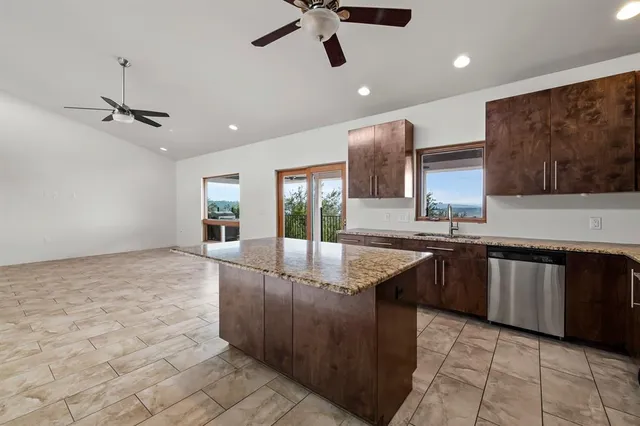 a large kitchen with granite countertop a sink and dishwasher a stove with wooden floor