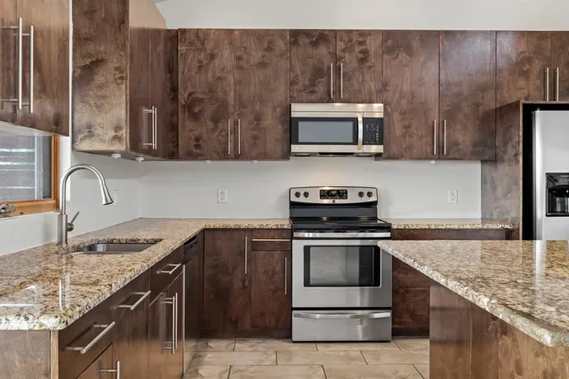 a kitchen with stainless steel appliances granite countertop a sink stove and microwave