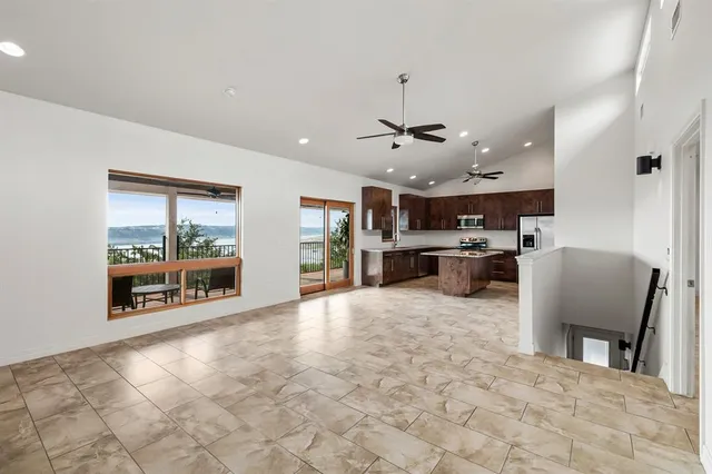 a large hall with stainless steel appliances furniture a large window and a kitchen view